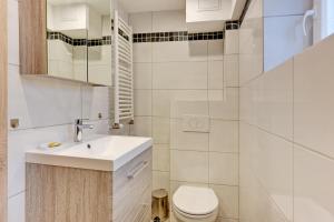 a white bathroom with a sink and a toilet at Villa Arkodes in Gdańsk