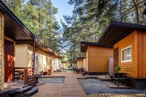 a wooden deck next to a cabin with trees at Po Švyturiu in Šventoji