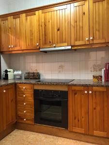 uma cozinha com armários de madeira e uma máquina de lavar louça preta em Casa San Nicolás em Morella