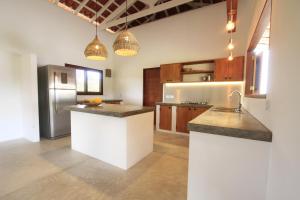 a kitchen with white counters and a stainless steel refrigerator at Villa Estrelas Atins in Atins