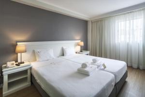 una camera d'albergo con un grande letto bianco con due lampade di Hotel Gaivota Azores a Ponta Delgada