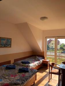 a bedroom with two beds and a table and a window at Pokoje z łazienkami - DZIWNÓWEK in Kamień Pomorski