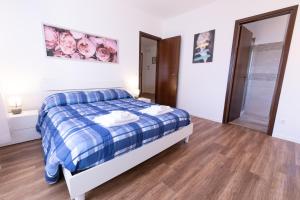 a bedroom with a blue and white bed and wooden floors at Casa di ALICE in Tolmezzo