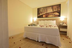um quarto com uma cama branca e uma pintura na parede em Hotel Amsterdam Montes Claros em Montes Claros