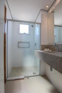 a glass shower in a bathroom with a sink at Hotel Amsterdam Montes Claros in Montes Claros