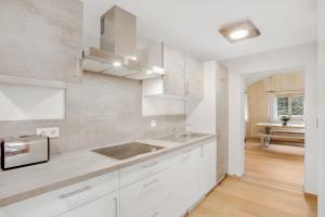 a white kitchen with white cabinets and a sink at Ferienwohnung Uferweg in Fischbachau