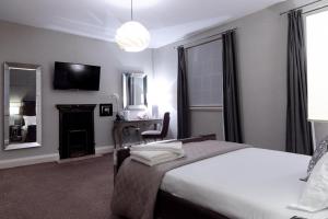 a bedroom with two beds and a desk and a mirror at The City Rooms in Leicester