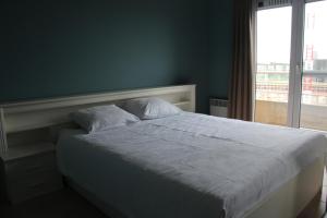 a bedroom with a white bed with a window at Marina Mercator in Ostend