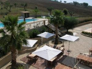 eine Gruppe von Tischen und Sonnenschirmen neben einem Pool in der Unterkunft Agriturismo Raggioverde in Recanati