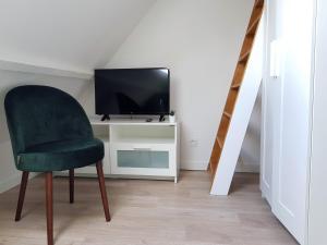 a living room with a green chair and a television at Le Fleury - Studio calme proche de Rouen in Déville-lès-Rouen