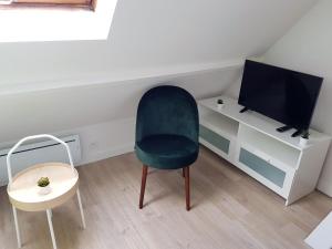 a living room with a chair and a tv at Le Fleury - Studio calme proche de Rouen in Déville-lès-Rouen