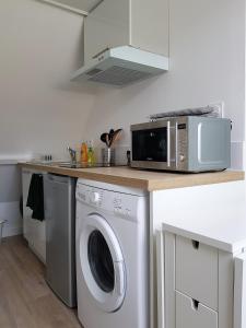 a kitchen with a washing machine and a microwave at Le Fleury - Studio calme proche de Rouen in Déville-lès-Rouen