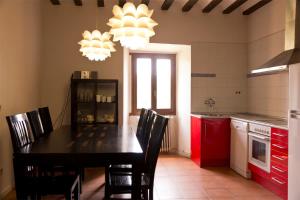 uma cozinha com uma mesa preta, cadeiras e armários vermelhos em Casa rural Casa fuerte San Gregorio II em Almarza