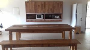 a wooden table in a kitchen with a microwave at Pousada Tia Tuquinha in Piumhi