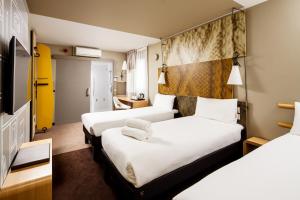 a hotel room with two beds and a tv at ibis London City - Shoreditch in London