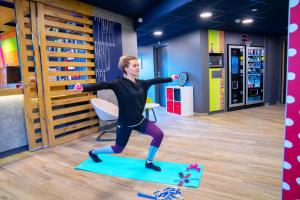 een man die een yoga pose doet op een mat in een kamer bij ibis budget Reims Parc Des Expositions in Reims