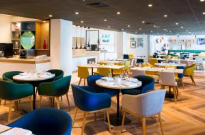 a restaurant with tables and chairs in a room at Holiday Inn London - Wembley, an IHG Hotel in London