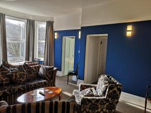 a living room with blue walls and couches and a table at 2 Bedroom Apartment at Kent Escapes Short Lets & Serviced Accommodation Kent, Bouverie Escape Folkestone with Wifi in Folkestone