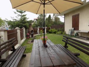 a wooden table with an umbrella in a backyard at Pokoje Goscinne MAXIM in Białogóra
