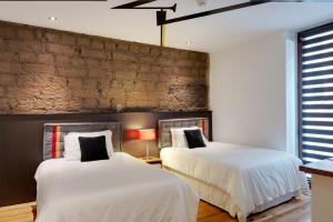 2 camas en una habitación con una pared de ladrillo en Hotel Casa Gardenia en Quito