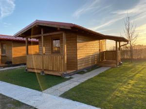 a log cabin with a porch and green grass at Chata pri jazere - 6km od Slovakia Ringu in Horná Potôň