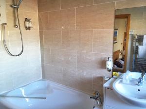 a bathroom with a tub, sink and mirror at Leapark Hotel in Grangemouth