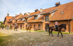 a group of people riding horses in front of a building at Pałac Galiny in Bartoszyce- Galiny