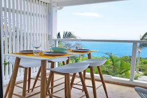 a table with chairs and wine glasses on a balcony at LA BOHEME, résidence de 5 appartements avec piscine, vue océan, Petite Ile in Petite Île