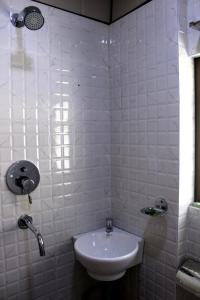 ein Badezimmer mit einem Waschbecken und einer weiß gefliesten Wand in der Unterkunft Horizon Homestay in Tānsen