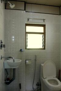 ein Bad mit einem Waschbecken, einem WC und einem Fenster in der Unterkunft Horizon Homestay in Tānsen