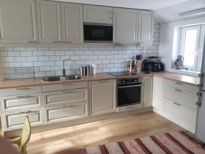 a kitchen with white cabinets and a sink at Lövnäs - Eget Hus utan andra gäster in Sörsjön