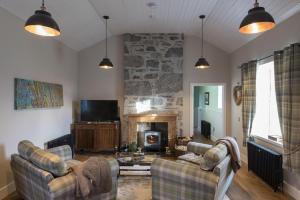 a living room with two couches and a stone fireplace at Evelix, The Old School House in Muir of Ord