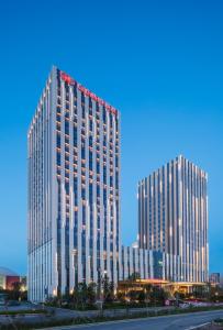 twee hoge gebouwen in een stad 's nachts bij Crowne Plaza Harbin Songbei, an IHG Hotel in Harbin