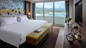 a bedroom with a large bed and a large window at ANA InterContinental Manza Beach Resort by IHG in Onna
