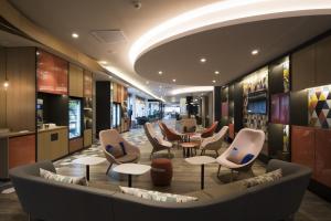 a lobby with chairs and tables in a building at Holiday Inn Express - Paris - CDG Airport by IHG in Roissy-en-France