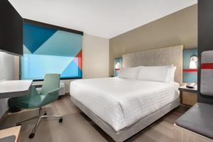 a bedroom with a bed and a desk and a chair at avid hotel Oklahoma City - Quail Springs by IHG in Oklahoma City