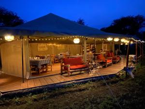 a tent with chairs and tables and lights on a deck at Zawadi Camp in Serengeti