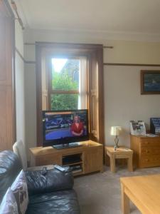 a living room with a flat screen tv and a couch at Dunclutha Guest House in Leven