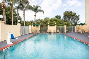 a swimming pool at a resort with palm trees at La Quinta by Wyndham Melbourne Viera in Melbourne