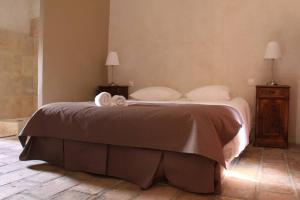 ein Bett mit einer braunen Decke und weißen Kissen in der Unterkunft Ancienne Abbaye de Franquevaux Anciennes Ecuries in Franquevaux