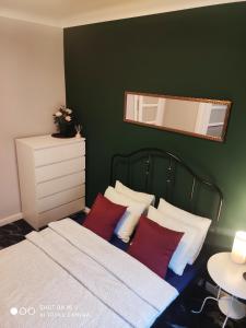 Schlafzimmer mit grünen Wänden und einem Bett mit roten Kissen in der Unterkunft Apartament Nina in Warschau