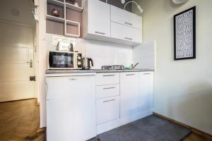 a kitchen with white cabinets and a microwave at Elegant Apartment Copernicus in Warsaw