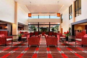 eine Lobby eines Hotels mit roten Stühlen und Tischen in der Unterkunft Ontario Airport Hotel & Conference Center in Ontario
