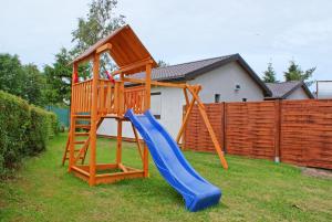 a playground with a blue slide in a yard at Baltic Resort Darłówko - Domek nr 2 in Darlowko