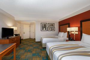 a hotel room with two beds and a flat screen tv at La Quinta by Wyndham Denver Southwest Lakewood in Lakewood