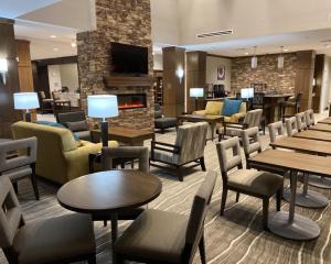 eine Hotellobby mit Tischen, Stühlen und einem Kamin in der Unterkunft Staybridge Suites - Denton, an IHG Hotel in Denton