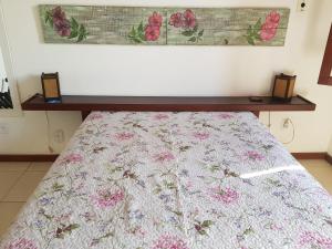 Una cama en una habitación con un edredón de flores. en Charmosa casa com piscina em Búzios, en Búzios