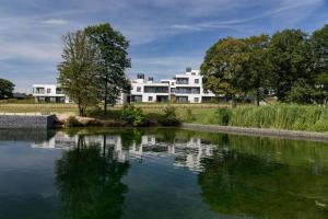 a building in the background with a lake in the foreground at Golden Lakes Hotel in Boussu-lez-Walcourt