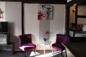 Habitación con sillas moradas, mesa y pintura en Appartement les Violettes, en Colmar