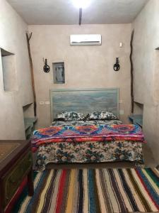 ein Schlafzimmer mit einem Bett mit einer bunten Bettdecke in der Unterkunft Grand Sud, la maison de sable in Douz